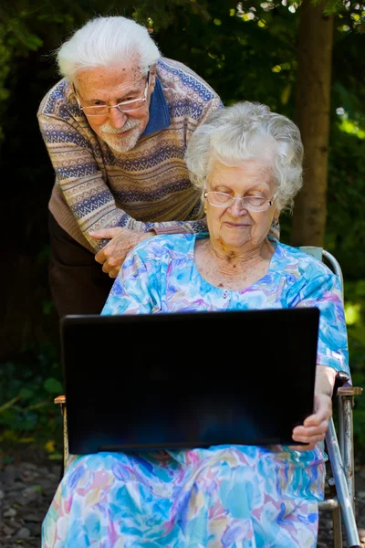 Casal de idosos se divertindo com o laptop ao ar livre — Fotografia de Stock