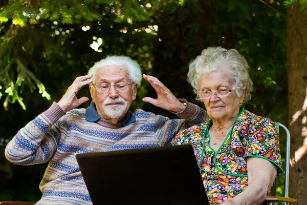 Casal de idosos se divertindo com o laptop ao ar livre — Fotografia de Stock