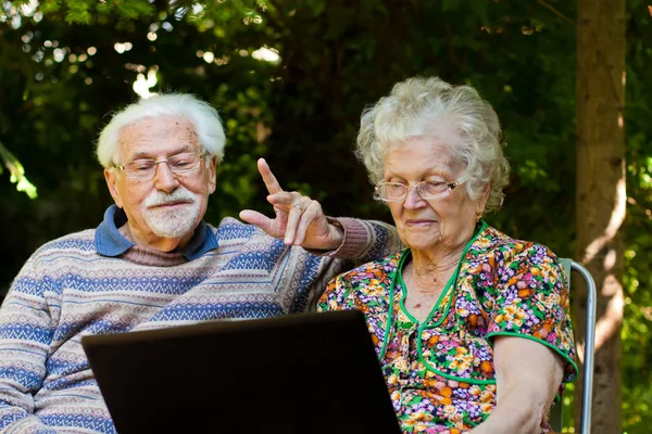 Casal de idosos se divertindo com o laptop ao ar livre — Fotografia de Stock