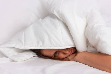 Uykusuzluk konsepti. Beyaz battaniyenin altında uyuyan kadın.