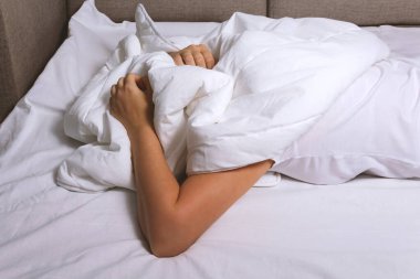 Uykusuzluk konsepti. Kadınlar ellerini beyaz battaniyeye koyar.