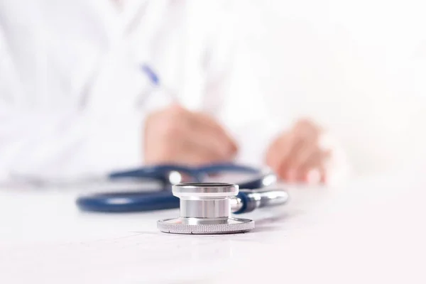 Steteskop yakın çekim. Beyaz üniformalı bulanık doktor..
