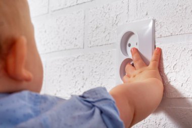 Tanımlanamayan beyaz çocuk açık elektrik priziyle oynuyor. Bebek telleri. Açık elektrik prizi ile tehlikeli oyunlar. 