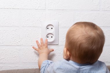 Tanımlanamayan beyaz çocuk açık elektrik priziyle oynuyor. Bebek telleri. Açık elektrik prizi ile tehlikeli oyunlar. 