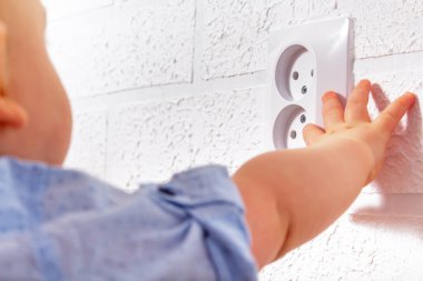 Tanımlanamayan beyaz çocuk açık elektrik priziyle oynuyor. Bebek telleri. Açık elektrik prizi ile tehlikeli oyunlar. 