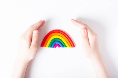 Plastiksi gökkuşağının etrafındaki eller. LGBT aile kavramı. Üst Manzara. Gey bayrağının renkleri. Hafif arkaplan.