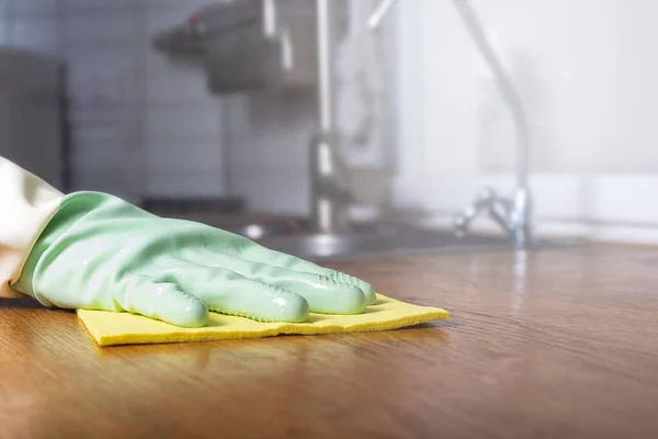 Cleaning kitchen with green rubber glove. Close-up.