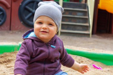 Kum havuzunda oturan şirin küçük çocuk. Yakın plan..