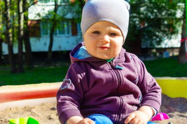 Kum havuzunda oturan üzgün küçük çocuk. Yakın plan..