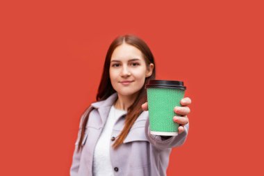 Elinde kahve bardağı tutan genç bir kadın..