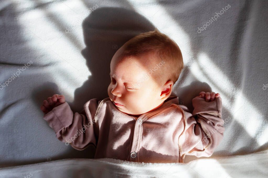 Newborn baby sleeping home in morning sunlights. 