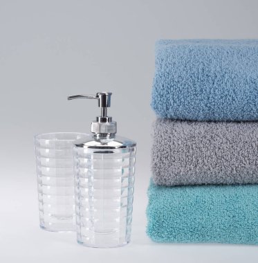 Açık arkaplanda sıvı sabun dağıtıcısı olan gri havlu.