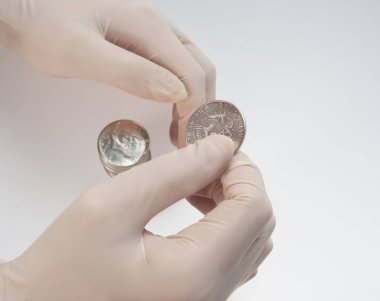 kauçuk eldivenli eller beyaz arka planda gümüş bir Amerikan doları tutuyor