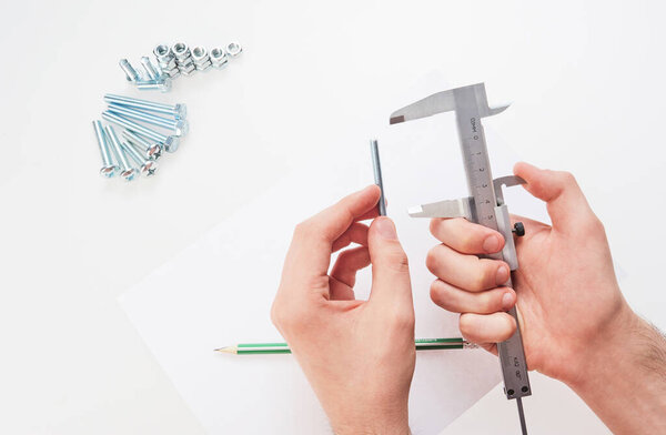 hands with a caliper measure bolts and nuts. on white background  