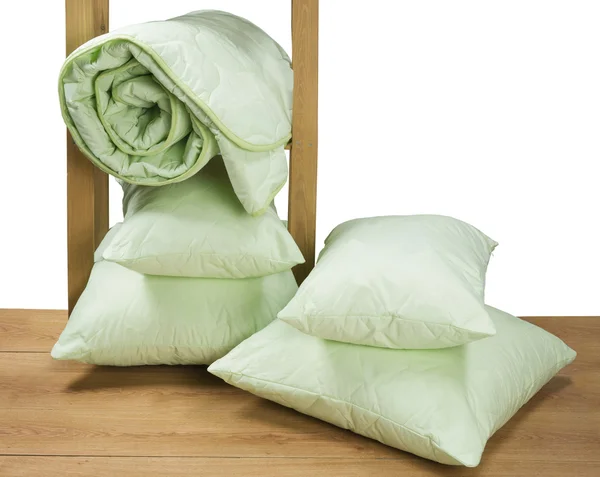 Verdes cobertor torcido e travesseiros em uma prateleira — Fotografia de Stock