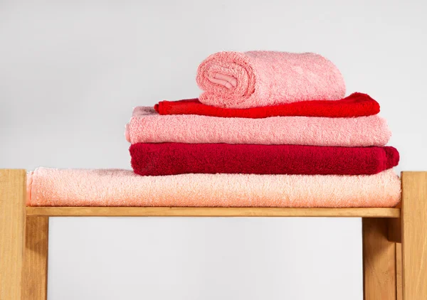 Set of colorful towels on wooden shelf — Stock Photo, Image