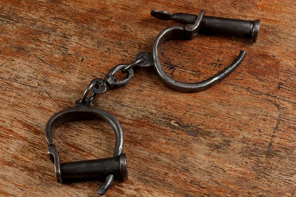 Vintage metal handcuffs on the wooden table — Stock Photo, Image