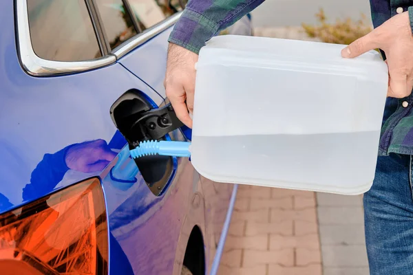 Feche o homem enchendo um fluido do motor diesel da lata para o tanque de carro azul. Fluido de escape diesel para redução da poluição do ar. Solução ecológica e ecológica. — Fotografia de Stock