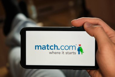 Man 's Hand' deki cep telefonu ekranındaki logoyu eşleştir. Randevu ve tanıdıklık başvurusu. Adam kanepede yatıyor ve internete ortak arıyor. Online randevu.