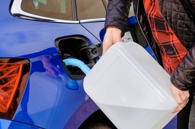 Mavi arabanın deposuna dizel motor sıvısı dolduran bir kadın. Hava kirliliğinin azaltılması için dizel egzoz sıvısı. 
