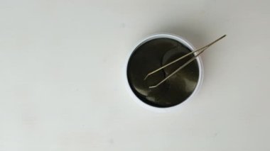 Siyah hidrojel yamalar ve cımbızlar etrafında dön. Deri bakımı konsepti. Kırışıklık önleyici maske kaldırılıyor.