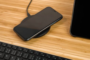 Cep telefonu tablet ve klavyenin yanında kablosuz şarj ediliyor.