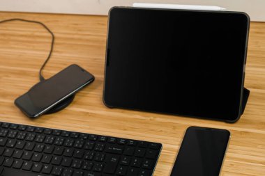 Cep telefonu, tabletin yanındaki kablosuz şarj cihazına dolgulu kalem ve klavye ile yükleniyor.