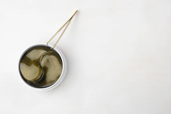 Top view on the jar with gold collagen hydrogel eye patches and ppenzers on the white background with copy space. — стоковое фото