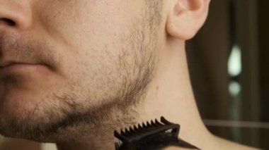 Tıraş olurken yüzünü ve sakalını elektrikli jiletle kesen bir adam. Tıraş olduktan sonra cilt tahrişi. 