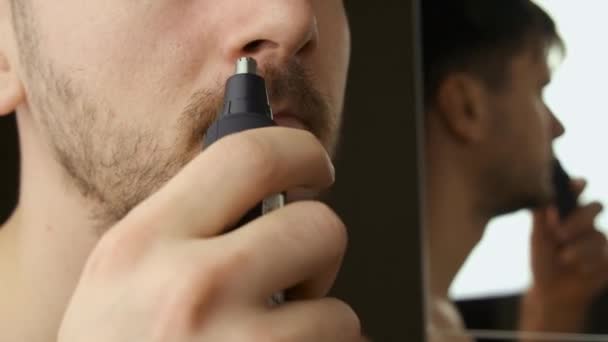 El hombre utiliza recortador de energía eléctrica para recortar el cabello en la nariz. Rutina diaria. — Vídeos de Stock