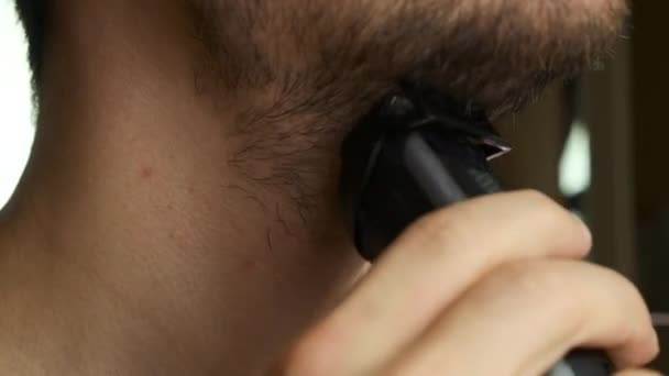 Zbliż faceta do golenia twarzy i brody brzytwą elektryczną. Podrażnienie skóry po goleniu. — Wideo stockowe