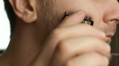 Tıraş olurken yüzünü ve sakalını elektrikli jiletle kesen bir adam. Tıraş olduktan sonra cilt tahrişi. 