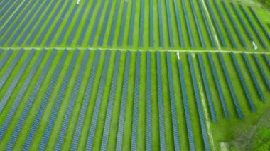 Elektrik üretimi için bir güneş enerjisi istasyonu üzerinden uçmak. Yeşil alanda dikey güneş panelleri var. Yenilenebilir çevre dostu enerji kaynağı.