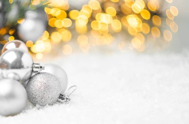 Noel ağacının arka planında karların üzerinde duran gümüş Noel topları ve fotokopi alanı ile bulanık altın ışıklar. Yeni yıl partisi için hazırlık.