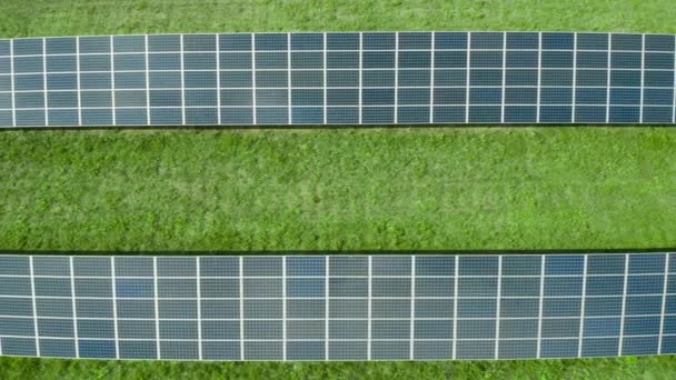 Полет вдоль солнечной панели на зеленом поле. Солнечная электростанция для производства зеленой энергии. Отражение неба в солнечной панели — стоковое видео