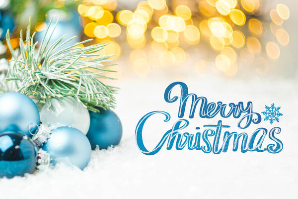 Merry Christmas greeting card in blue style with blurred lights on the background. 