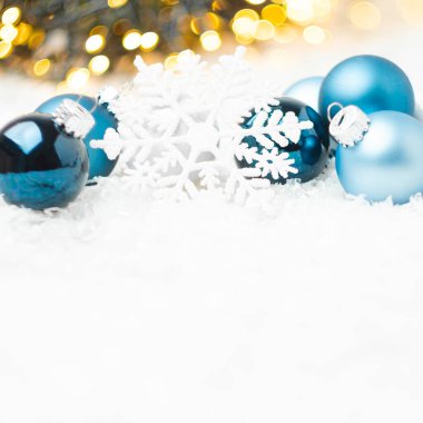 Mavi Noel topları ve kar taneleri, Noel ağacının arka planında karların üzerinde duruyor ve fotokopi alanı ile bulanık altın ışıklar. Yeni yıl partisi için hazırlık.