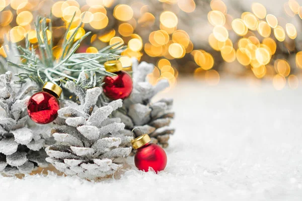 Cones de pinheiro e bolas vermelhas de Natal na neve. Decoração de inverno com espaço de cópia. — Fotografia de Stock