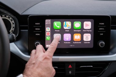 Close up mans hand touching an icon in the Apple Carplay on car dashboard screen, September 2020, San Francisco, USA clipart