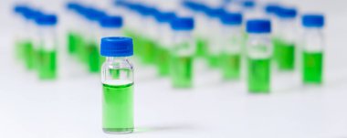 Beyaz arka planda mavi kapaklı HPLC tüpündeki yeşil bitki özü. İlaç veya aşı konseptinin geliştirilmesi.