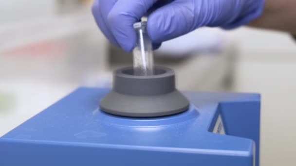 Chemik w gumowych rękawiczkach potrząsający próbkami używając wiru. Rozwój leków i środków farmaceutycznych — Wideo stockowe