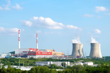 Panoramic view on nuclear power plant with steaming cooling towers on the background of blue sky. clipart