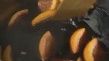 Noel şarabı yapmak ya da portakal dilimleri ve baharatlarla punç yapmak. Tahta kaşıkla karıştırılmış.. 