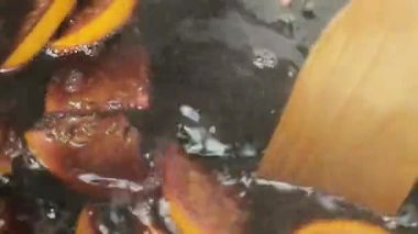Noel şarabı yapmak ya da portakal dilimleri ve baharatlarla punç yapmak. Tahta kaşıkla karıştırılmış.. 