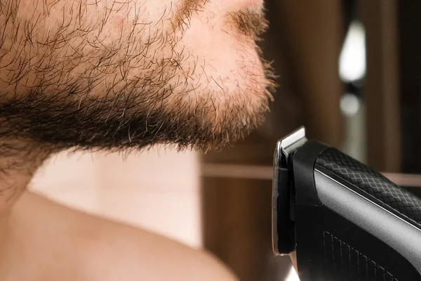 Вид спереди на человека, брившего щеку электрической бритвой — стоковое фото
