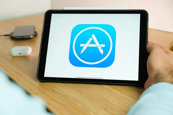 App store logo on the screen of iPad tablet with smart phone iPhone charging on the wireless charger and airpods in the case on the background, Νοέμβριος 2020, Σαν Φρανσίσκο, ΗΠΑ — Φωτογραφία Αρχείου