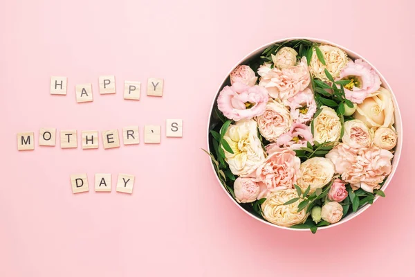 Happy Mother Day Schriftzug auf den hölzernen Quadraten mit Buchstaben auf dem rosa Hintergrund und große runde Schachtel mit roten Blumen und Rosen. Grußkarten-Konzept — Stockfoto