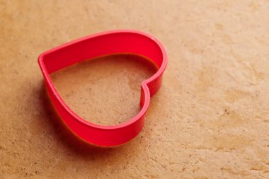 Hamurun üzerinde zencefilli kurabiye yapmak için kalp şeklinde pişirme kalıbı. Aziz Sevgililer Günü tatlıları