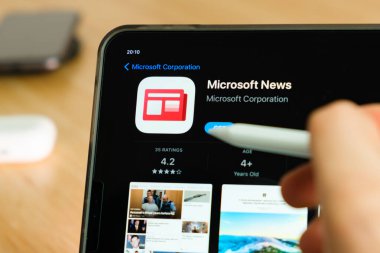 Microsoft News logo shown by apple pencil on the iPad Pro tablet screen. Man using application on the tablet. December 2020, San Francisco, USA.