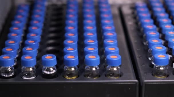 Automatizált szállítószalag automatikus mintavevő HPLC rendszer. Kék kupakos injekciós üvegek a tálcán. A vakcina és a gyógyszerek vizsgálata — Stock videók